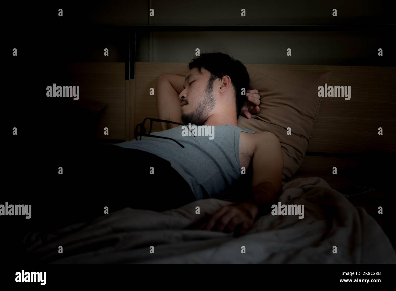 Schöner asiatischer junger Mann schläft gemütlich auf einem Bett in seinem Schlafzimmer in der Nacht. Stockfoto