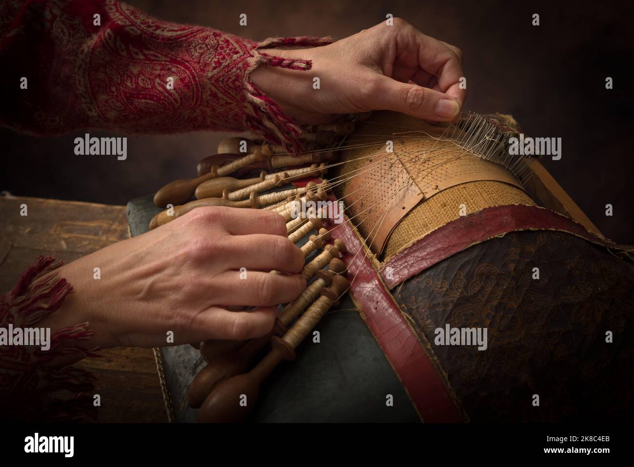 Hände einer Frau, die an einem antiken flämischen Kopfkissen zur Herstellung von Spitze arbeitet Stockfoto