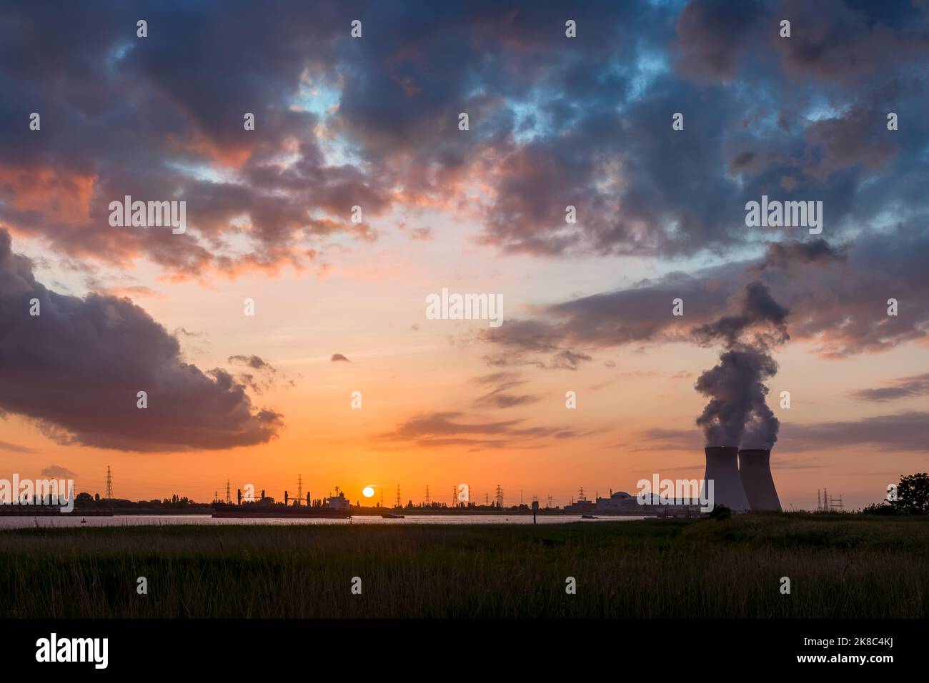 Farbenprächtiger Sonnenuntergang über dem Antwerpener Welthafen in Belgien mit Blick auf die Türme des Atomkraftwerks Stockfoto