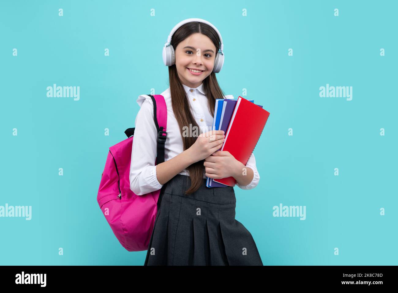 Schulmädchen, Teenager 12, 13, 14 Jahre alt, in Kopfhörern und Büchern auf isoliertem Studiohintergrund. Schulkinder mit Rucksack. Stockfoto