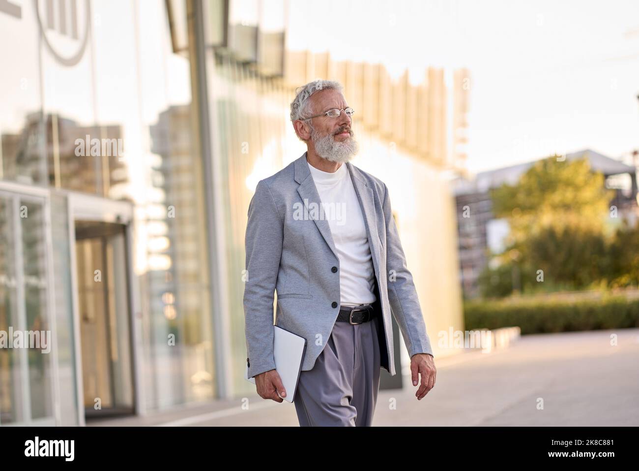 Glücklicher älterer, professioneller Geschäftsmann, der in der Großstadt draußen spazieren geht. Stockfoto