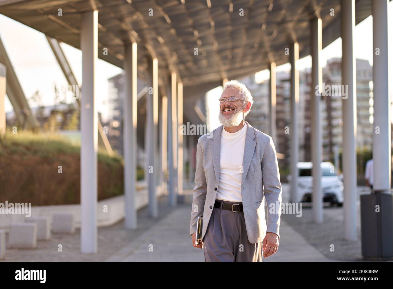 Fröhlicher, stilvoller alter Geschäftsmann, der in der Großstadt draußen unterwegs ist. Stockfoto
