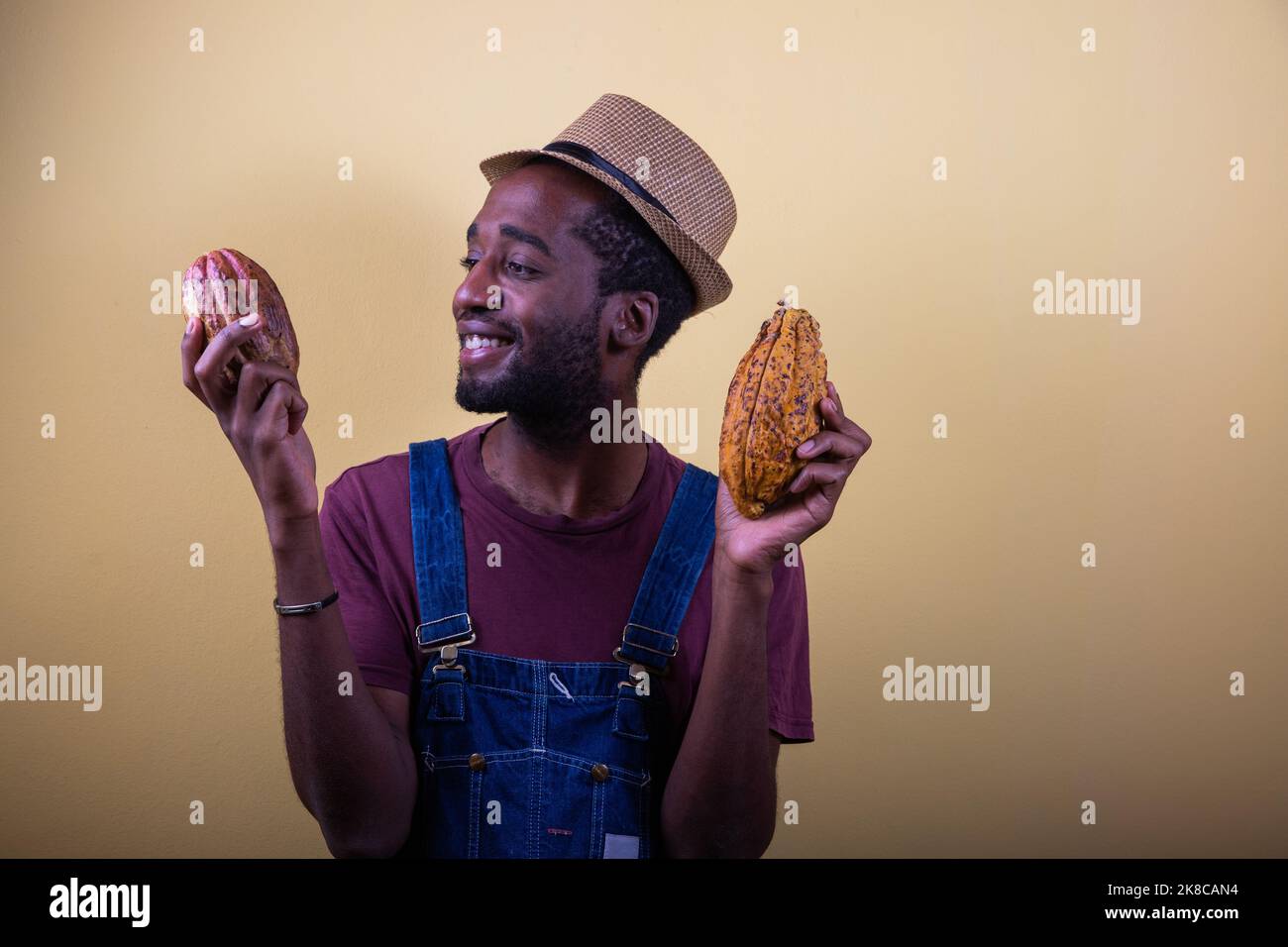 Ein afrikanischer Bauer schaut zufrieden mit seinen frisch geernteten Kakaoschoten, Foto im Studio Stockfoto