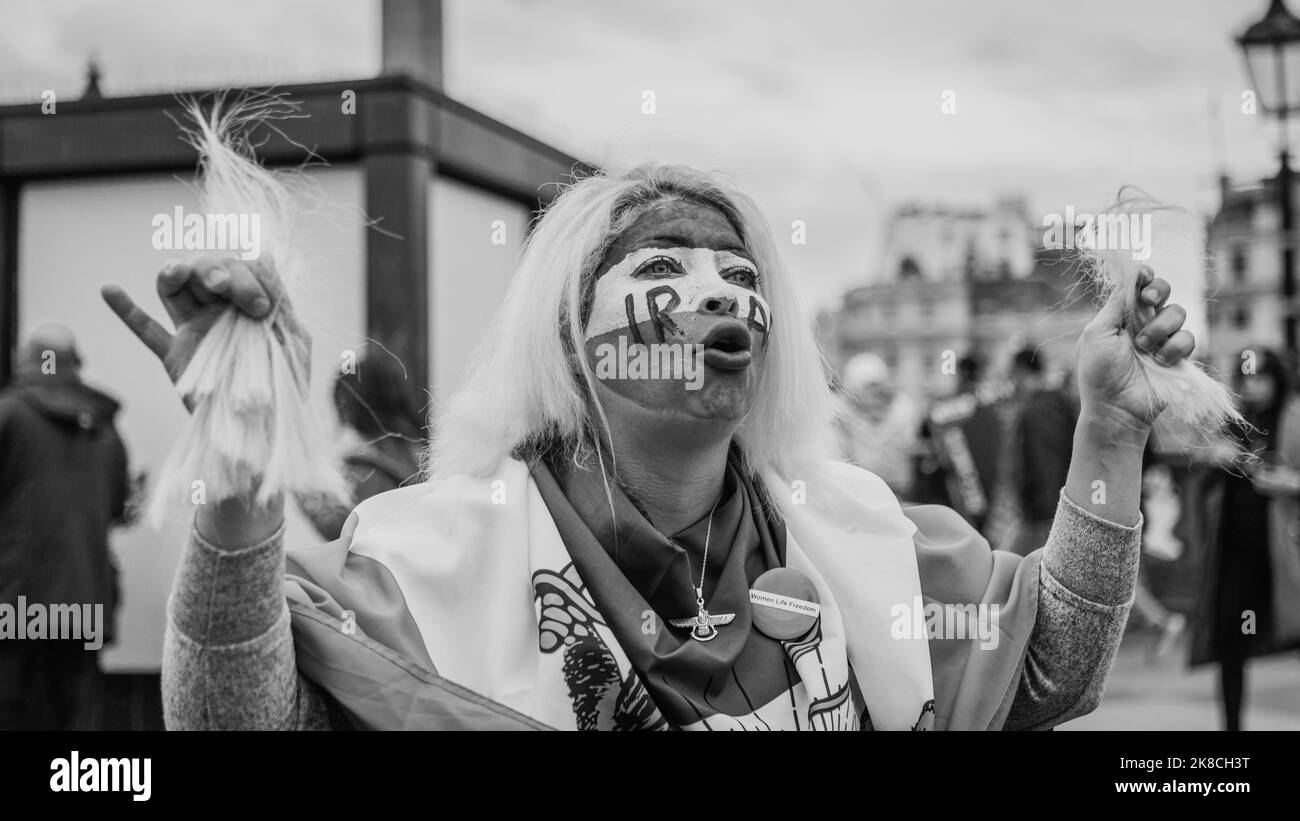 Schwarzweißes Bild einer Demonstrantin, die sich beim Protest „Woman, Life, Freedom“ in London zur Unterstützung unterdrückter iranischer Frauen die Haare schneidet. Stockfoto