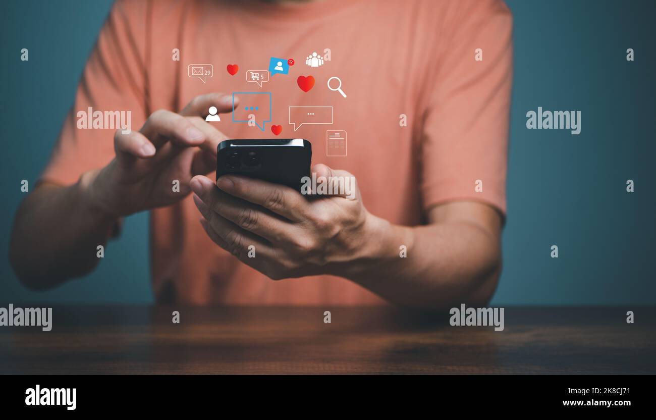 Mann, der Smartphone mit Social-Media-Symbolen verwendet, Liebe, Suche, Menschen, Gruppe, Einkaufen, Dokumente. Handy-Anwendung und Social-Media-Marketing-con Stockfoto