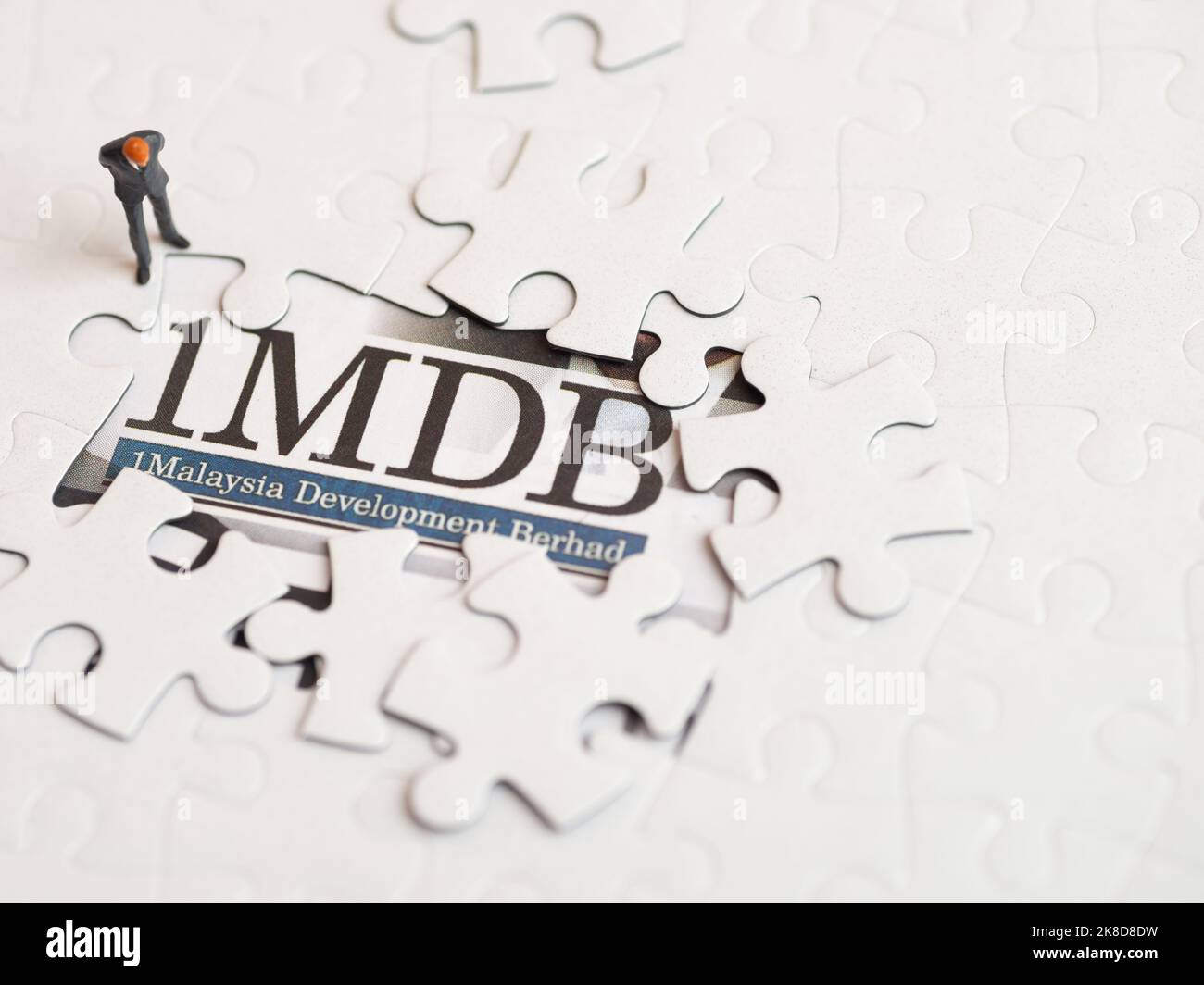 Illustrative Editorial von 1MDB Skandal Konzept - 1Malaysia Entwicklung Berhad kriminellen Fall-Miniatur-Figur eines Geschäftsmannes Blick auf Rätsel. Stockfoto