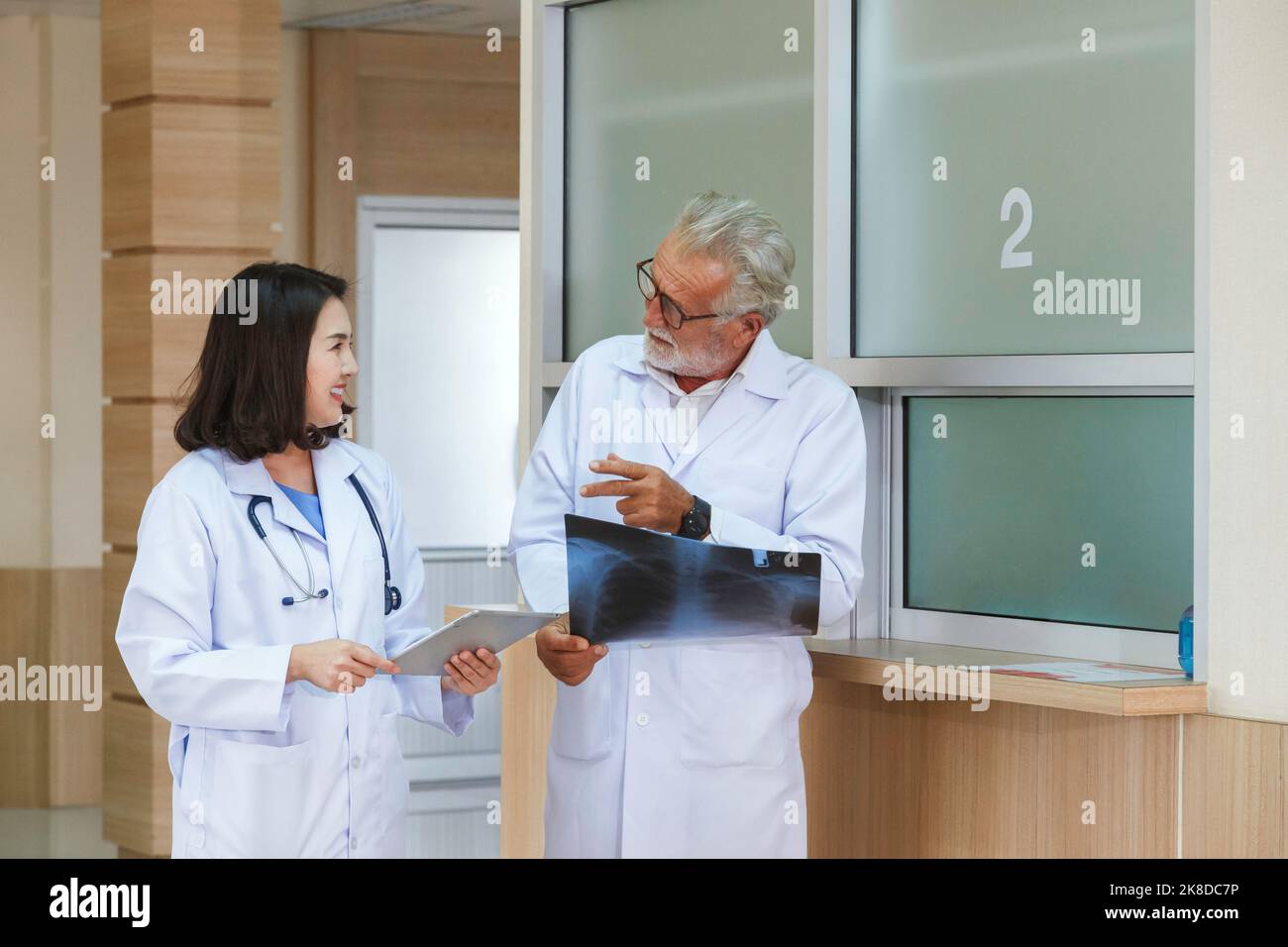 Expertise Senior chirurgische Blick auf Röntgenfilm zu beraten und zu diskutieren für die Operation Behandlung der Patient mit jungen asiatischen Frau Arzt in der hos Stockfoto