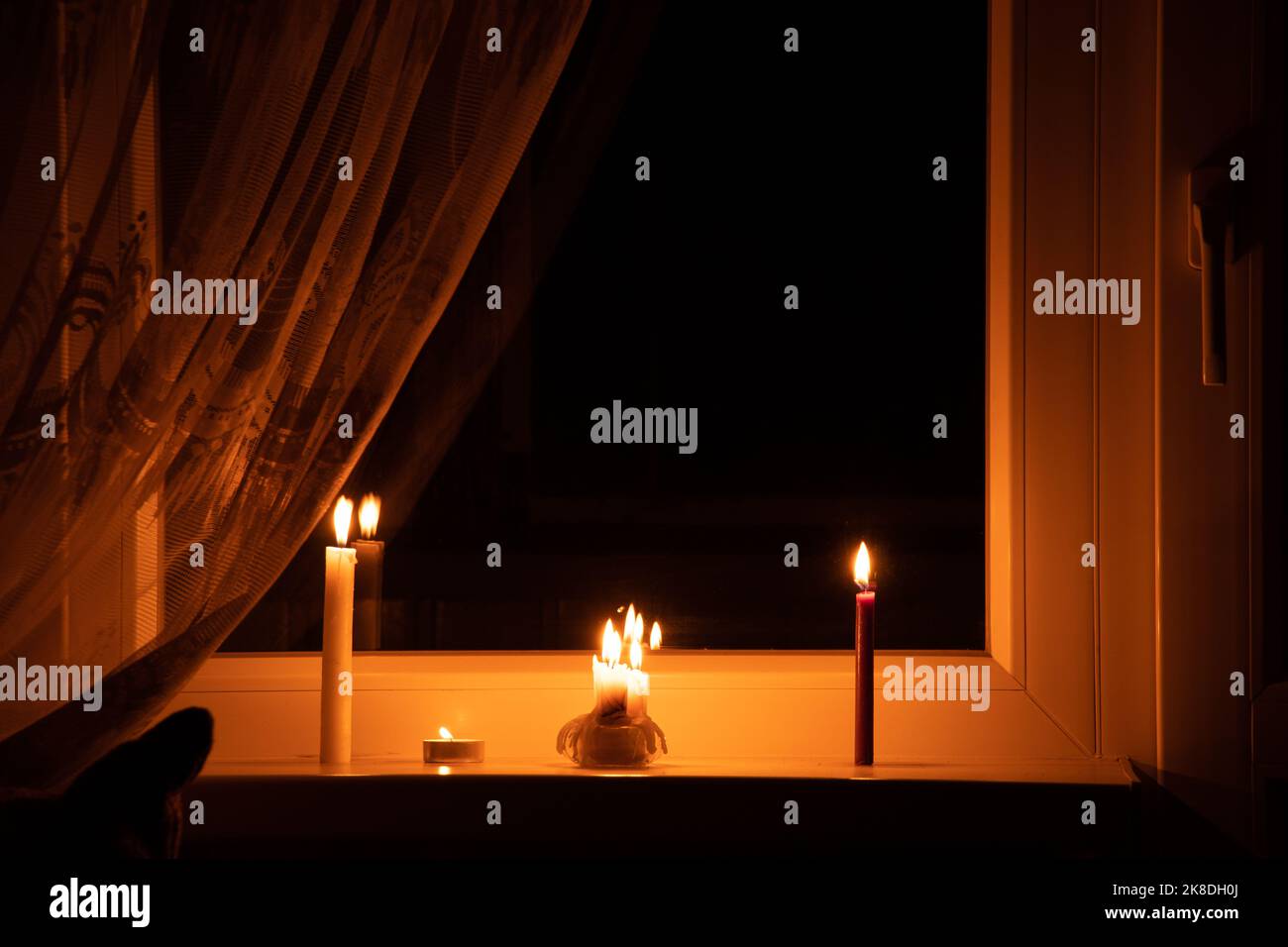 Kerzen auf dem Fenster in einer Wohnung in der Ukraine, Ukraine ohne Strom aufgrund des Krieges, eine Wohnung ohne Licht, das Licht einer Kerze in der Stockfoto Kerzen auf dem Fenster in einer Wohnung in der Ukraine, Ukraine ohne Strom aufgrund des Krieges, eine Wohnung ohne Licht, das Licht einer Kerze in der Stockfoto