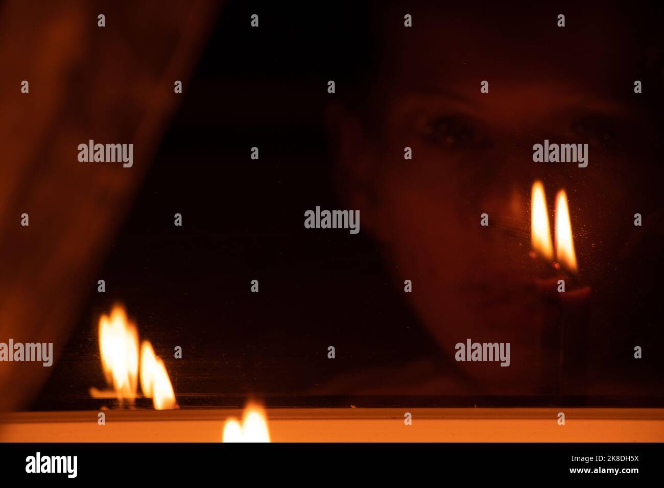 Das Gesicht des Mädchens setzte Kerzen auf das Fenster einer Wohnung in der Ukraine, in der Ukraine, die wegen des Krieges keinen Strom hatte, einer Wohnung ohne Licht Stockfoto Das Gesicht des Mädchens setzte Kerzen auf das Fenster einer Wohnung in der Ukraine, in der Ukraine, die wegen des Krieges keinen Strom hatte, einer Wohnung ohne Licht Stockfoto