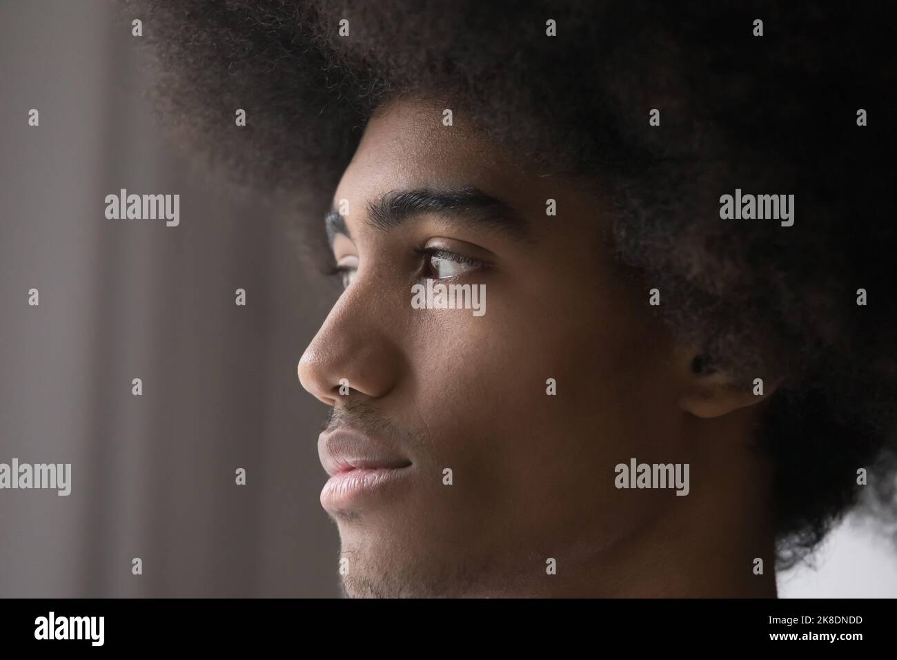 Ernster oder besorgter afrikanischer Kerl mit lockigen Haaren, der zur Seite starrt Stockfoto