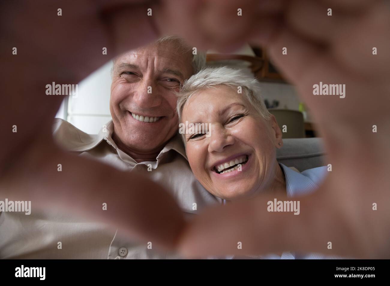 Glückliches älteres Paar, das der Kamera ein Symbol der Liebe zeigt Stockfoto