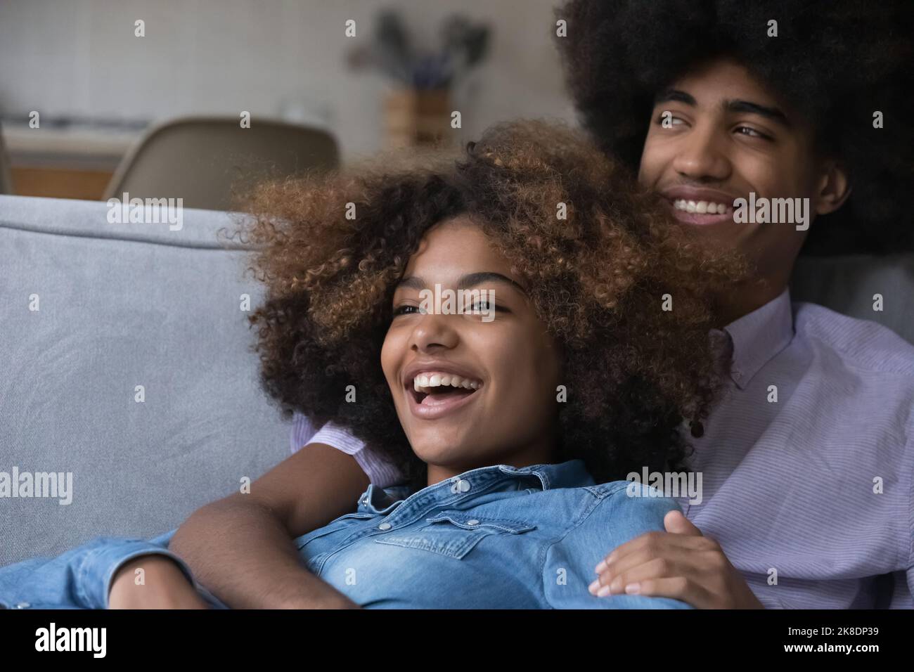 Schönes fröhliches afrikanisches Paar in der Liebe umarmt entspannend auf dem Sofa Stockfoto