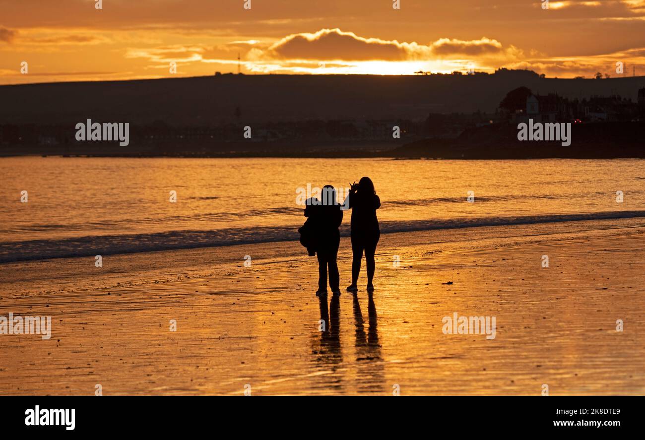 Portobello, Edinburgh, Schottland, Großbritannien. 23.. Oktober 2022. Sonnenaufgang am Meer am Firth of Forth für diejenigen, die früh zum Sport gehen oder um das Morgenlicht zu erwischen, Temperatur 10 Grad Celsius. Im Bild: Paare genießen das bunte Morgenlicht. Quelle: Arch White/alamy Live News. Stockfoto