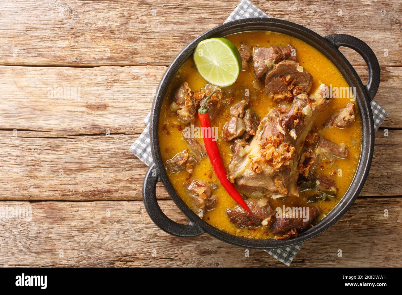 Indonesisches Essen Gulai Kambing Ziegenkurvig würziger Eintopf aus der Nähe auf der Pfanne auf dem Holztisch. Horizontale Draufsicht von oben Stockfoto
