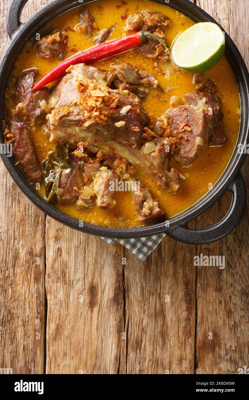 Gulai Kambing ist ein traditionelles indonesisches Essen, das ein reiches, würziges und sukkkkulentes, in der Pfanne auf dem Holztisch anhaltendes, herzliches und würziges Gericht enthält. Vertikal Stockfoto