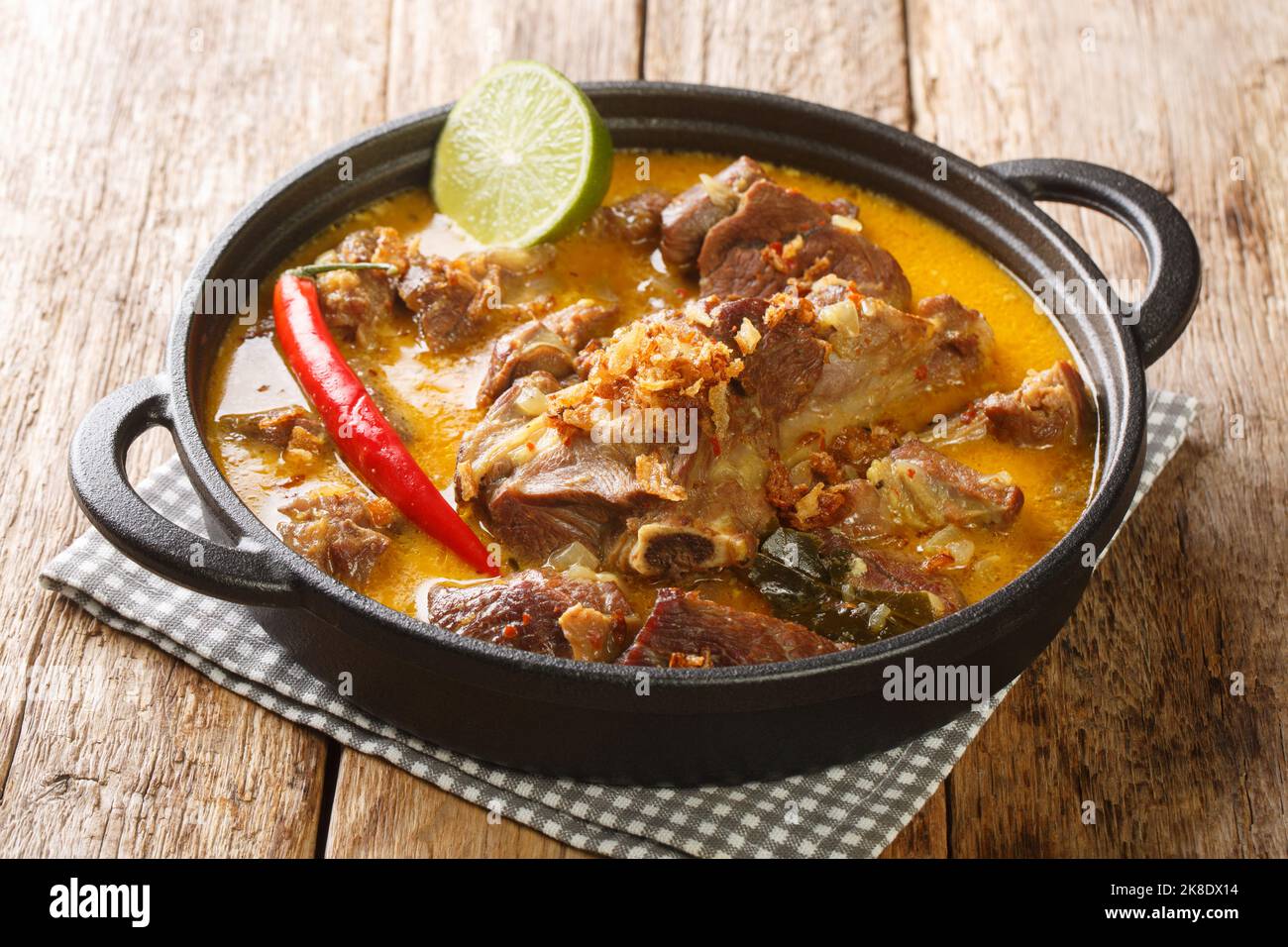 Indonesisches Essen Gulai Kambing Ziegenkurvig würziger Eintopf aus der Nähe auf der Pfanne auf dem Holztisch. Horizontal Stockfoto