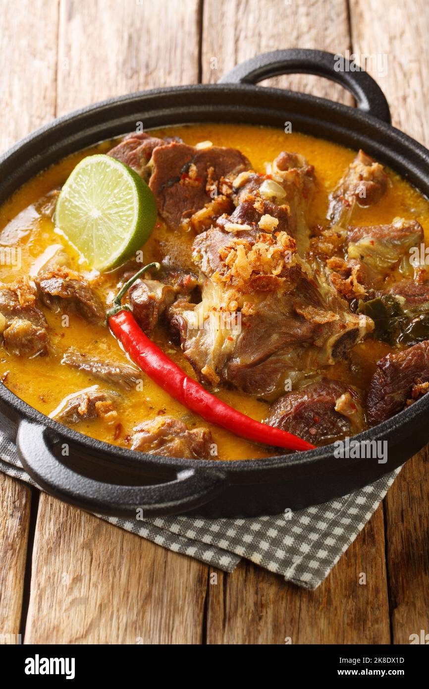 Lamb Curry oder indonesischer Gulai Kambing für Eid in der Pfanne auf dem Holztisch. Vertikal Stockfoto