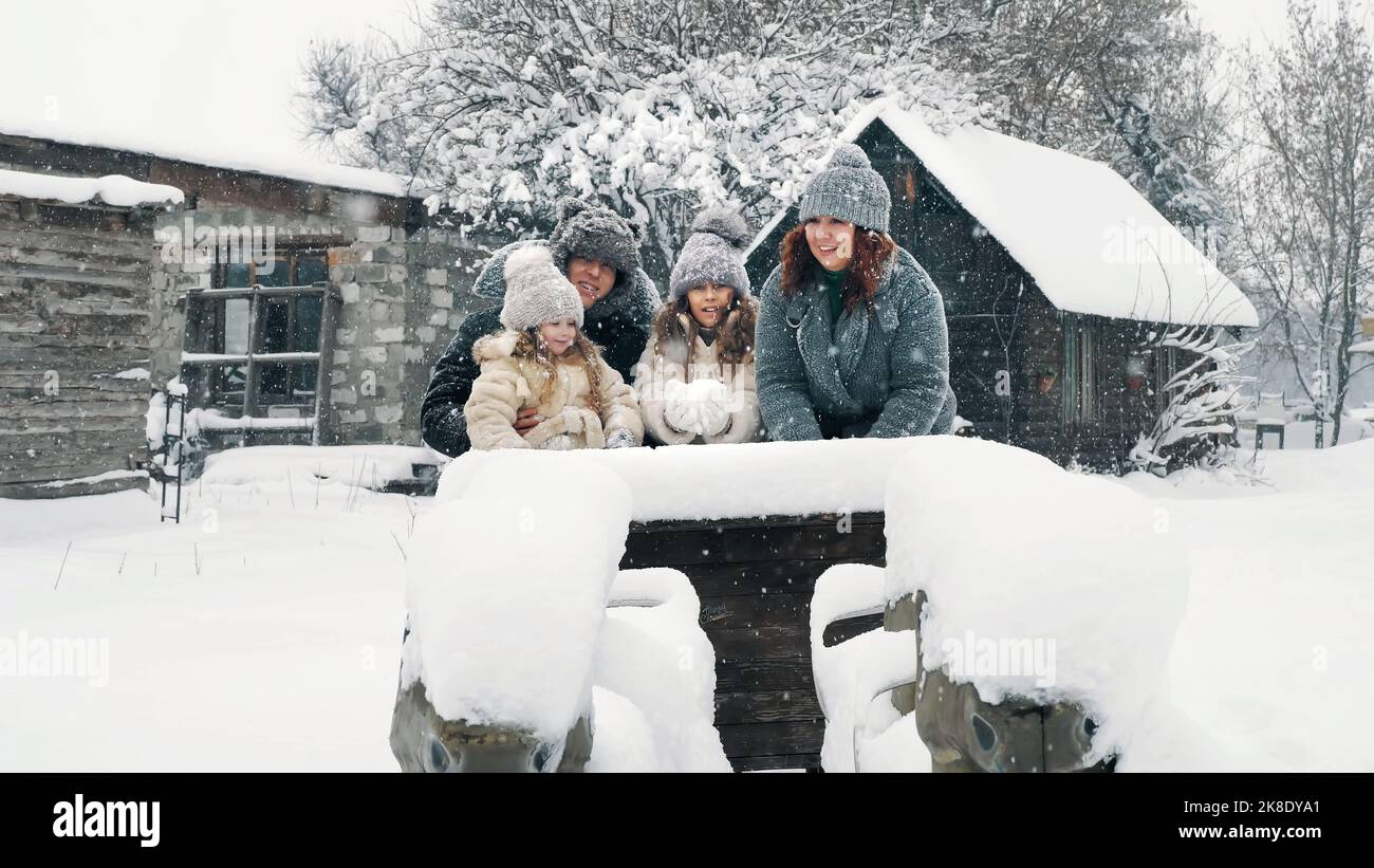 Winterspaß für die ganze Familie. Schnee werfen. Fröhliche, lachende, verspielte Familie von 4 Jahren genießt Schnee und Schneefall, hat Spaß und verbringt gemeinsam Zeit am verschneiten Wintertag. Zeitlupe. Hochwertige Fotos Stockfoto