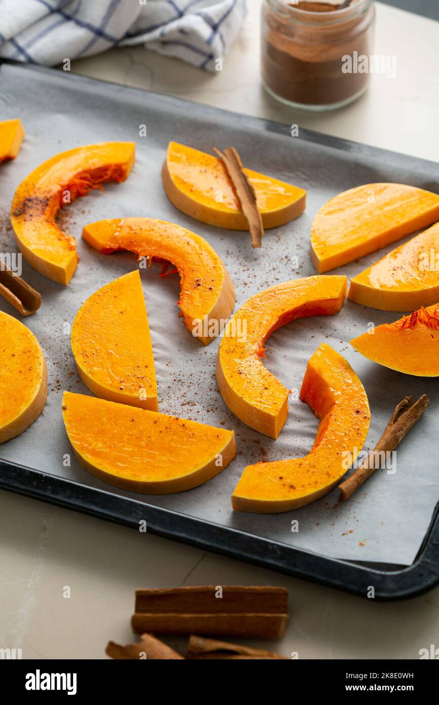 Kürbis in Scheiben geschnitten mit Zimt auf Backblech Kochen Lebensmittel Stockfoto