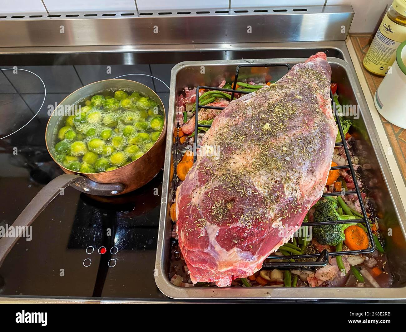 Rohe Lammkeule in einem Bräter mit Gemüse und Gewürzen. Hessen, Deutschland Stockfoto