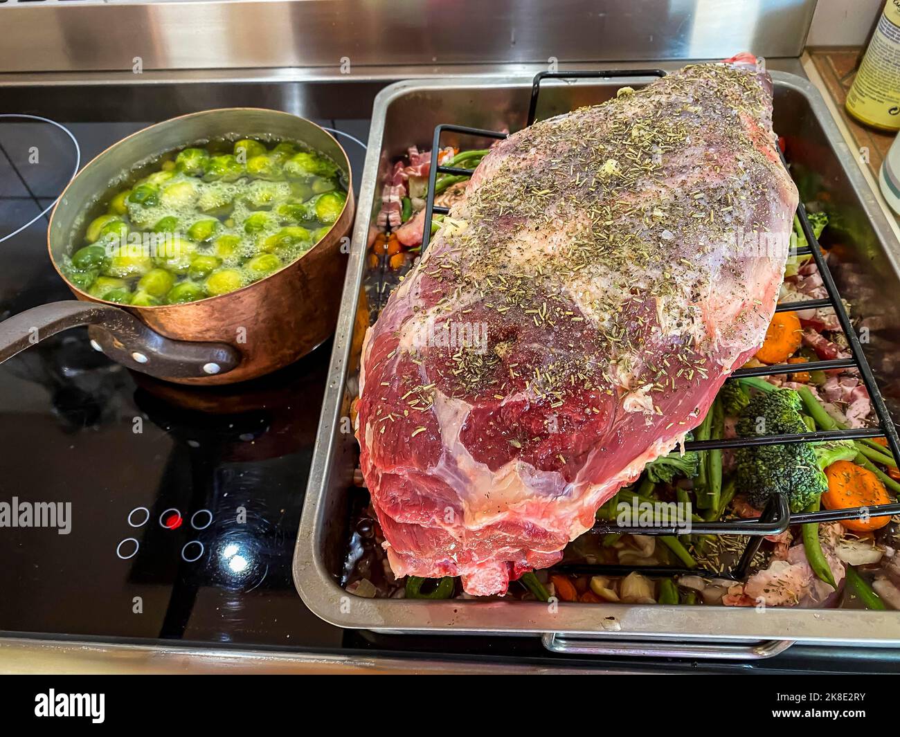 Rohe Lammkeule in einem Bräter mit Gemüse und Gewürzen. Hessen, Deutschland Stockfoto