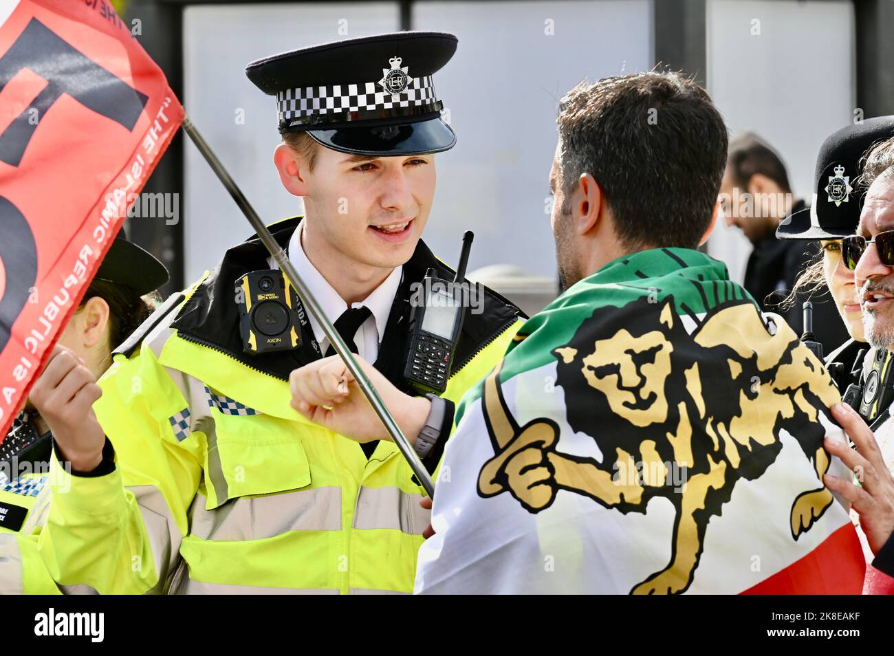 Ein junger Polizeibeamter protestiert mit einem Protestierenden. Kostenlose Iran-Demonstration, Trafalgar Square, London. VEREINIGTES KÖNIGREICH Stockfoto