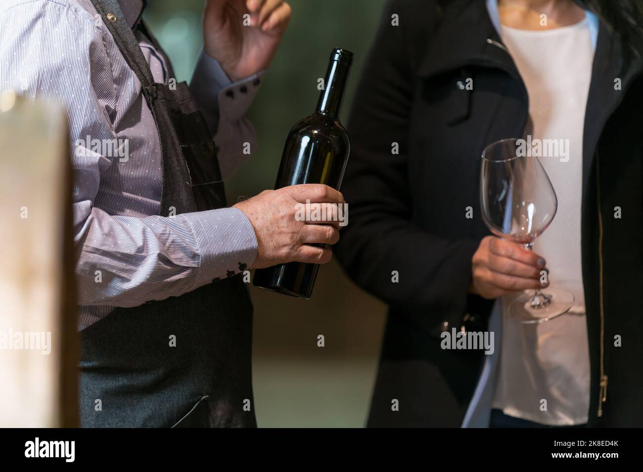 Hände gießen Rotwein aus einer Flasche in ein Glas in authentischen Weinkellern Stockfoto
