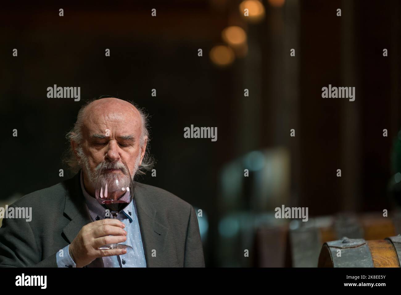 Älterer kaukasischer Tourist, Graubart eleganter Mann, der Rotwein in einem unterirdischen Weinkeller des Weinguts mit einer langen Tradition verkostet Stockfoto
