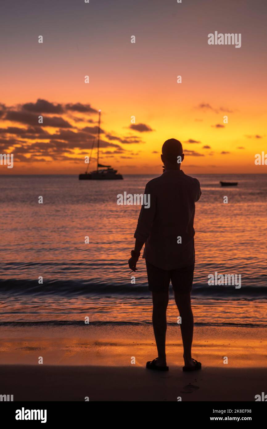 Ein einsamen Mann beobachtet den Sonnenuntergang in Beau Vallon, Seychellen Stockfoto