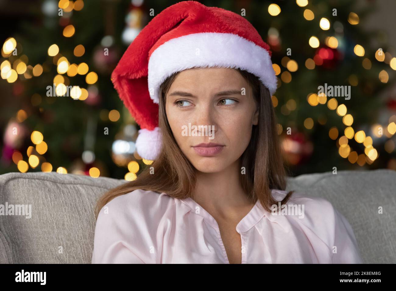 Unglückliche junge Frau, die Weihnachten allein zu Hause feiert. Stockfoto