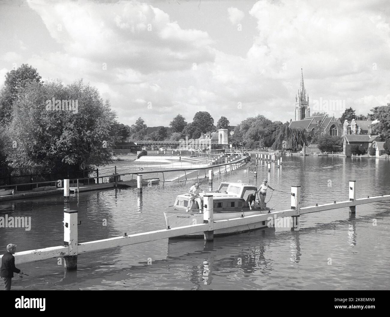 1966, historisch, Blick aus dieser Ära eines Vergnügungsbootes, das auf der Themse in Marlow, Bekshire, England, Großbritannien, festgemacht wurde. In der Ferne sieht man auf dem Bild die Hängebrücke über das Wehr und den Turm der All-Saint-Kirche. Stockfoto