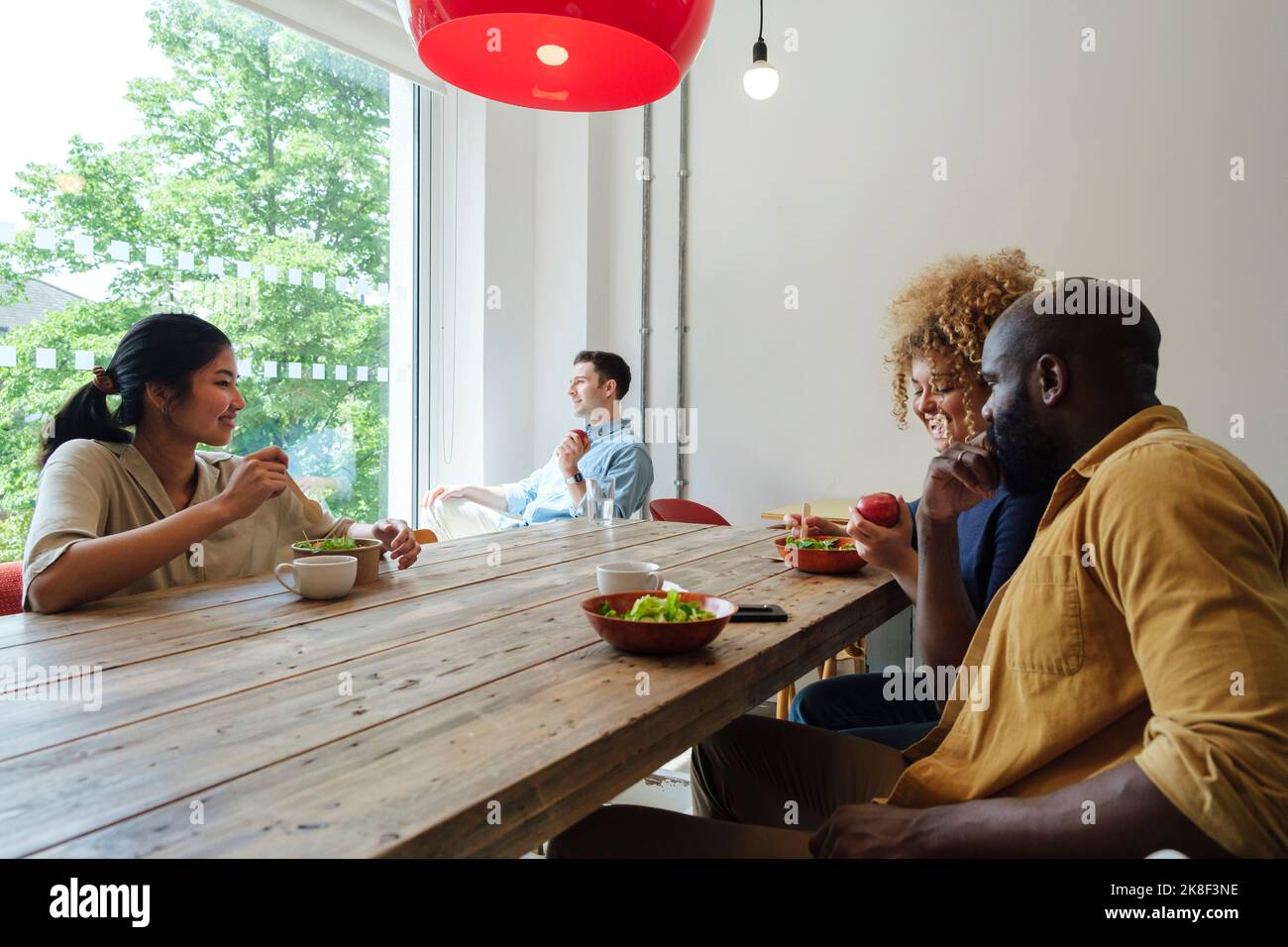 Geschäftsleute, die gemeinsam im Personalzimmer im modernen Büro ein gesundes Mittagessen einnehmen Stockfoto