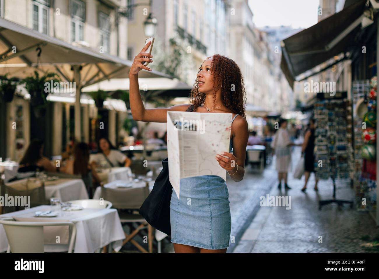 Junge Frau hält Karte und nimmt Selfie über Smartphone Stockfoto