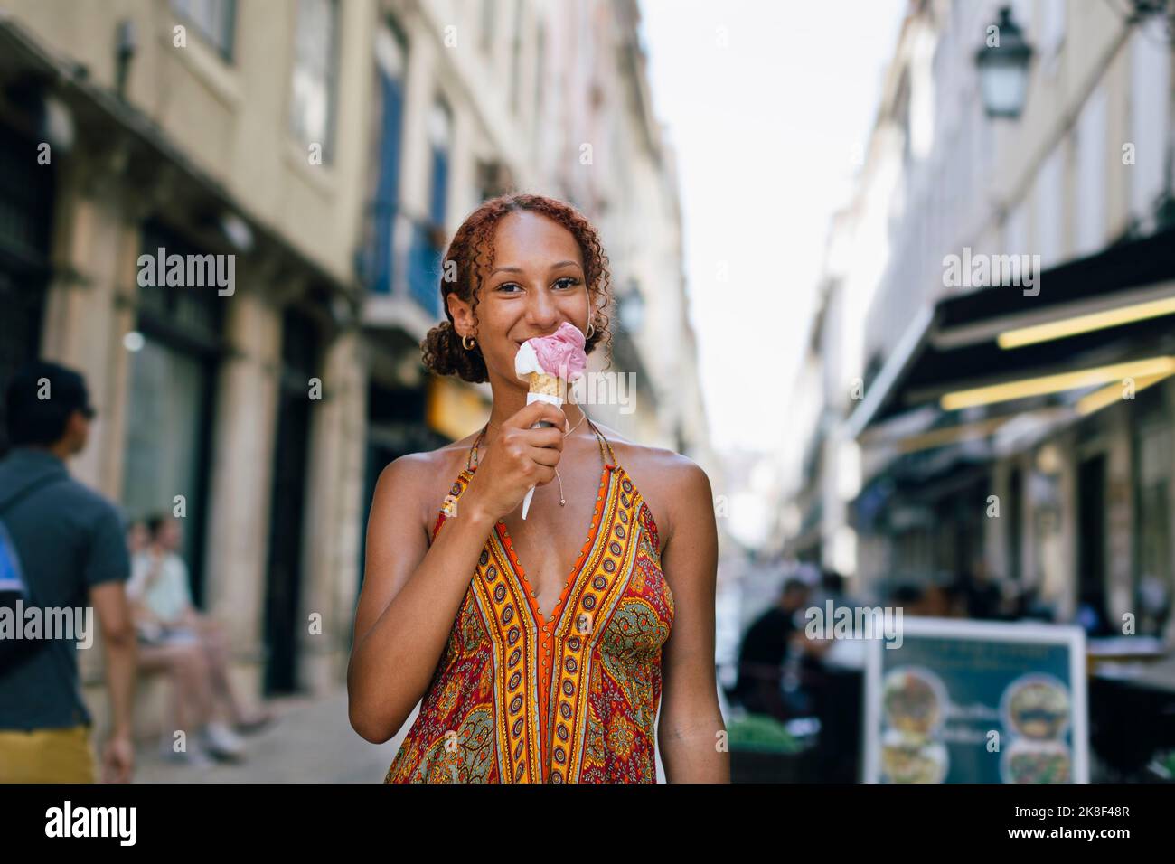 Lächelnde junge Frau leckt Eis Stockfoto