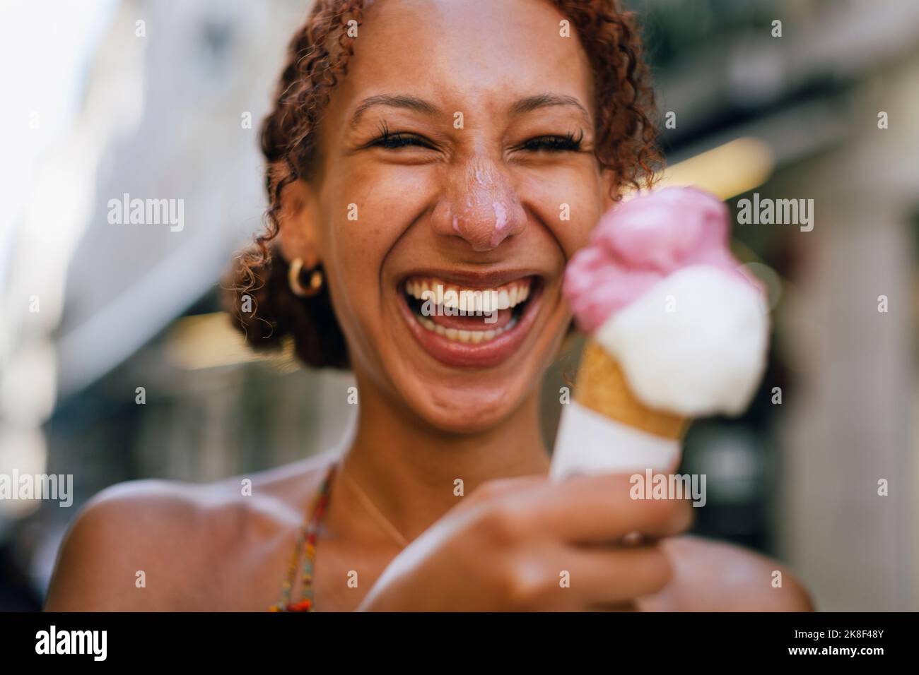 Fröhliche junge Frau, die Spaß mit Eis in der Hand hat Stockfoto