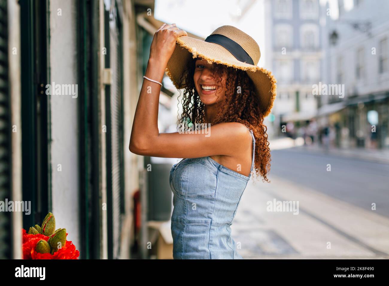 Glückliche junge Frau mit lockigen Haaren trägt Hut Stockfoto