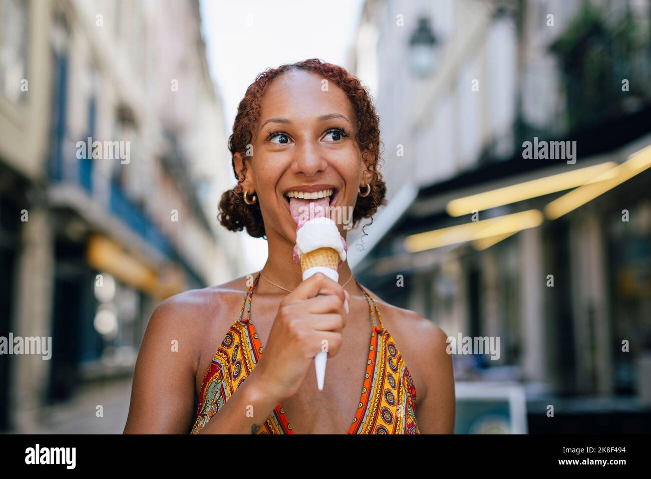 Glückliche junge Frau, die Eis leckt Stockfoto