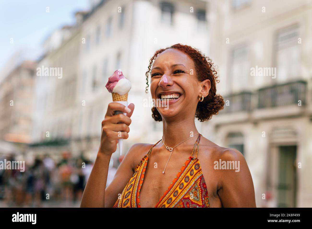 Fröhliche junge Frau mit lockigen Haaren, die Eis genießt Stockfoto