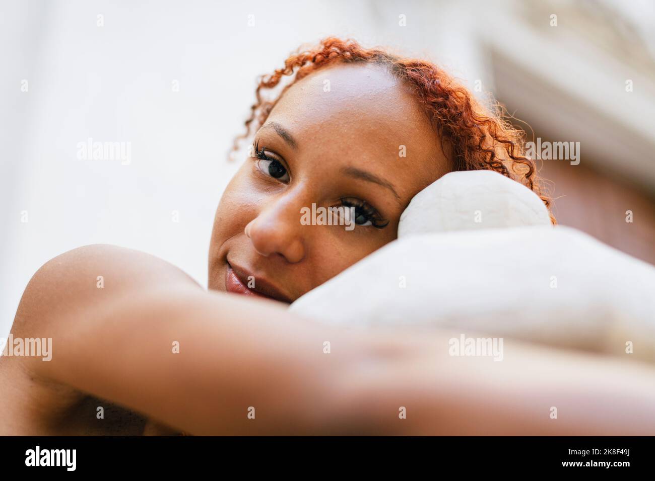 Junge Frau mit lockigen Haaren umarmt Poller Stockfoto