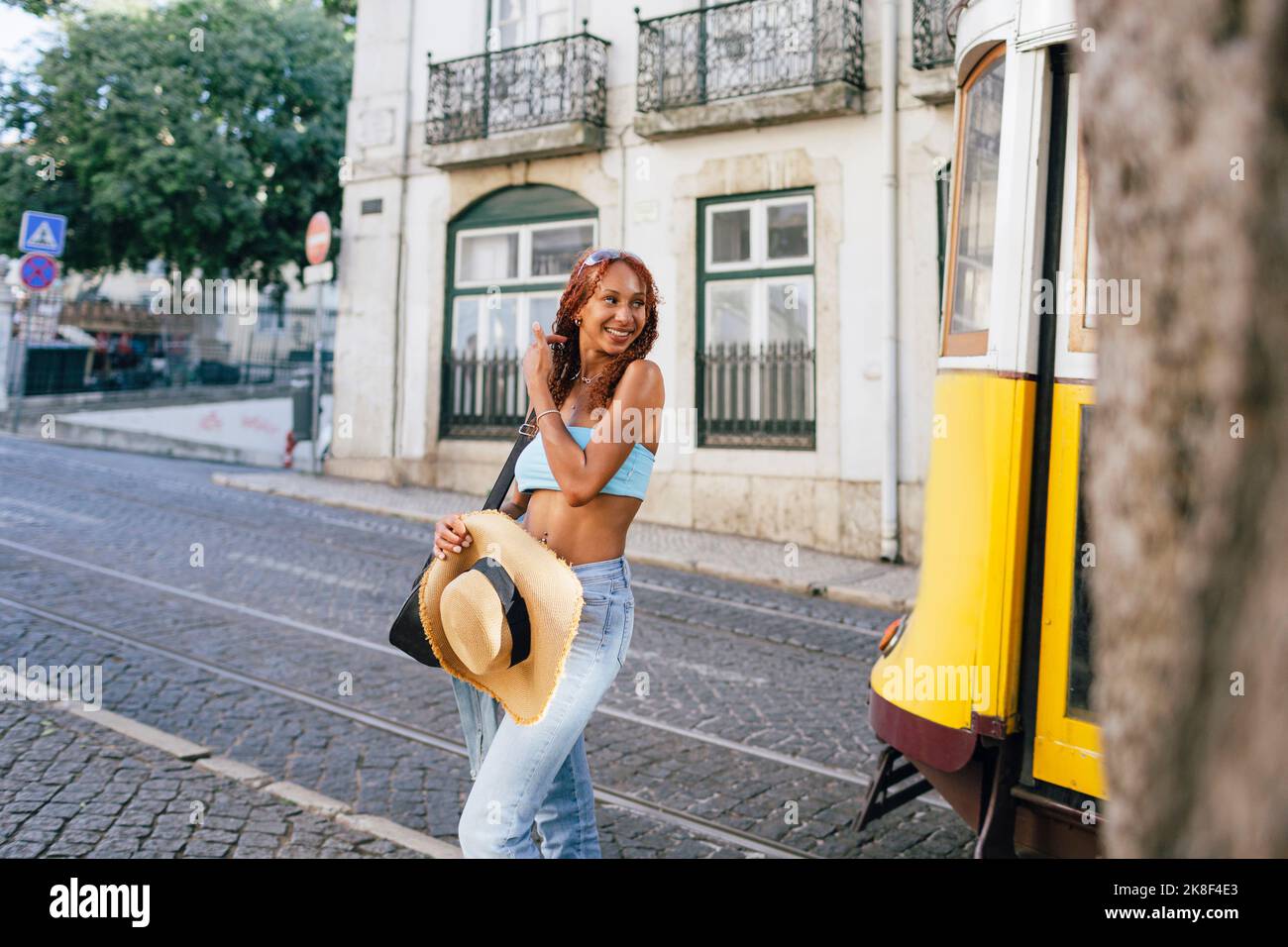Glückliche junge Frau, die mit der Seilbahn auf der Straße steht Stockfoto
