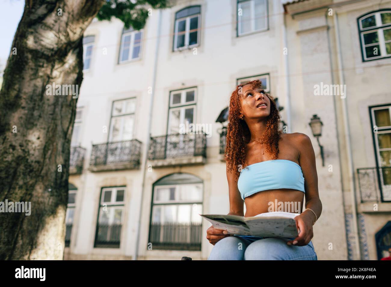 Junge Frau mit Karte vor dem Gebäude Stockfoto