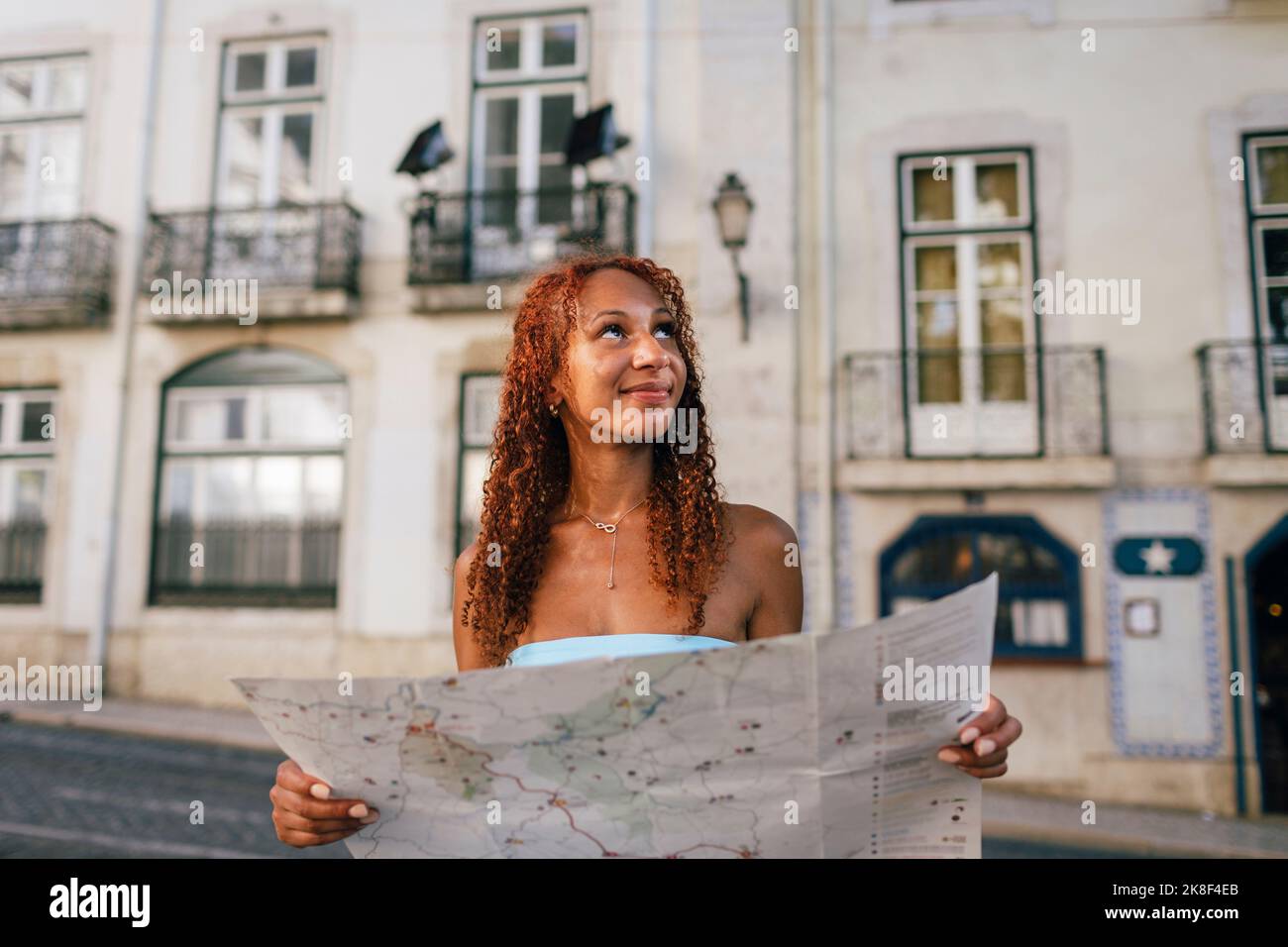 Lächelnde junge Frau mit Karte vor dem Gebäude Stockfoto