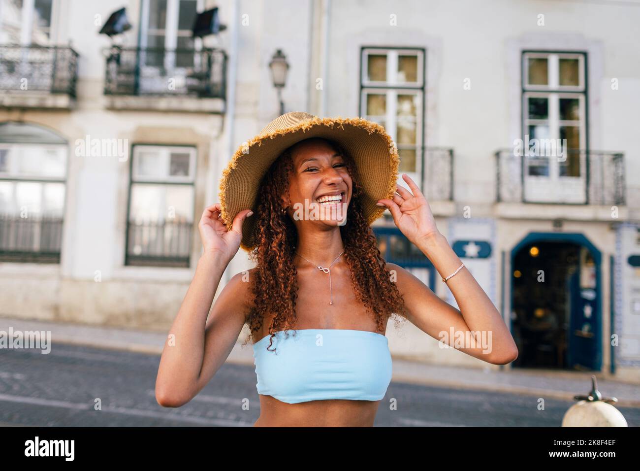 Glückliche junge Frau mit Hut vor dem Gebäude Stockfoto
