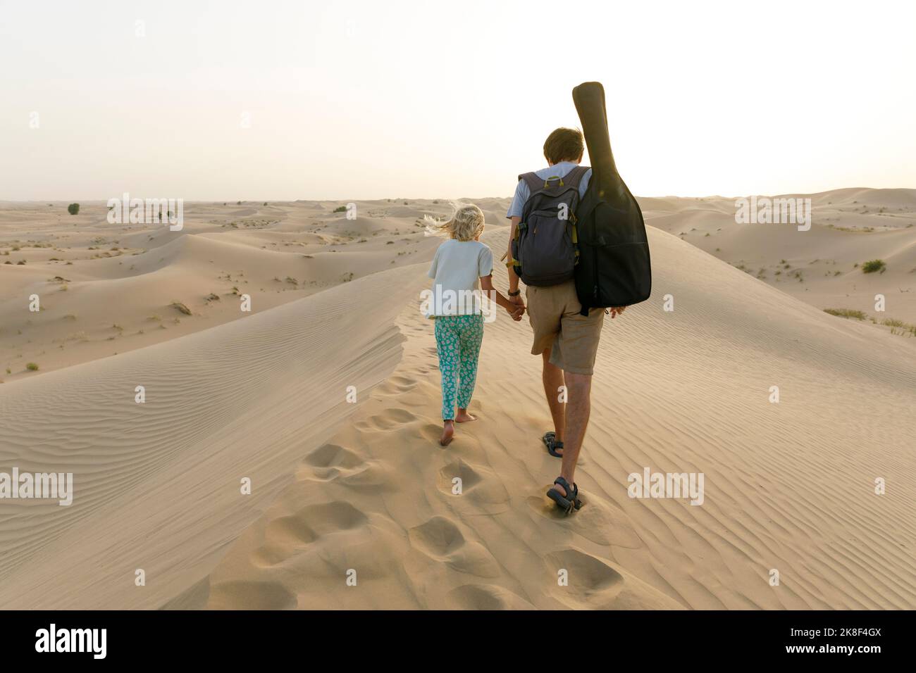 Vater hält die Hand der Tochter und geht auf Sanddüne in der Wüste Stockfoto