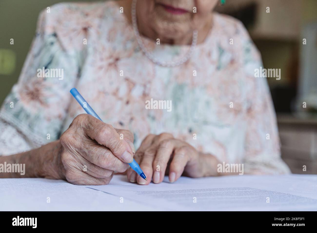 Ältere Frau, die Vertragsdokumente auf dem Tisch unterschrieb Stockfoto