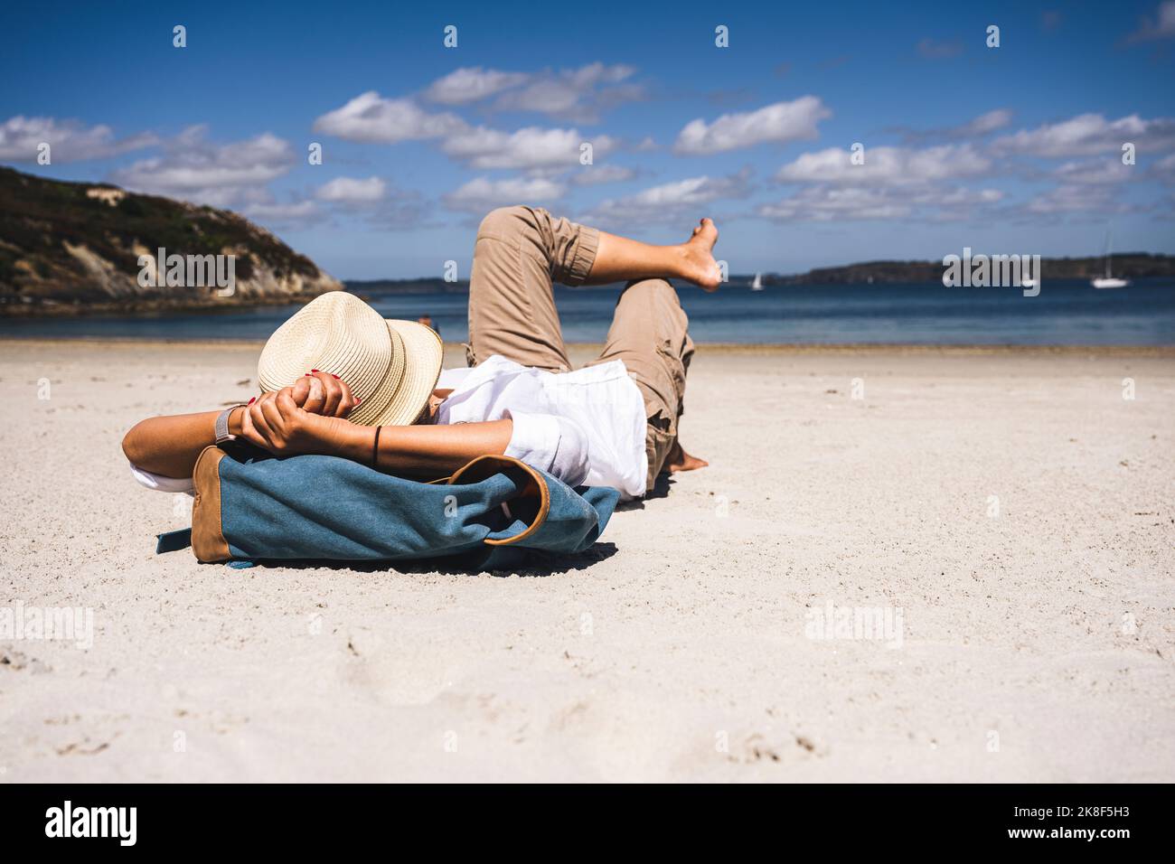 Reife Frau mit Hut und Rucksack im Urlaub entspannen am Strand Stockfoto