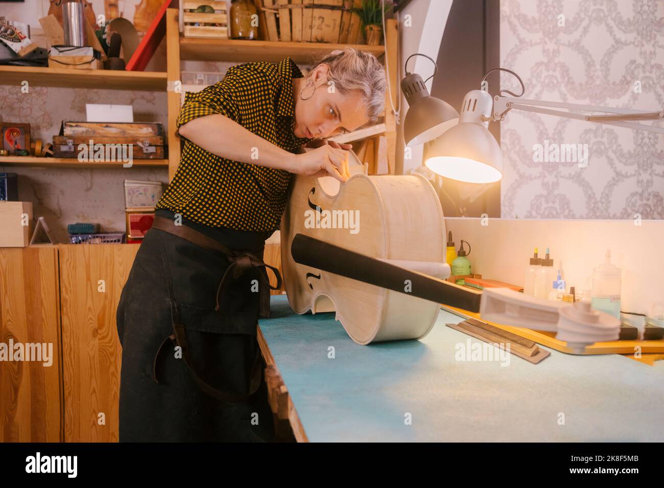 Instrumentenbauer mit Handwerkzeug, das in der Werkstatt am Kontrabass arbeitet Stockfoto