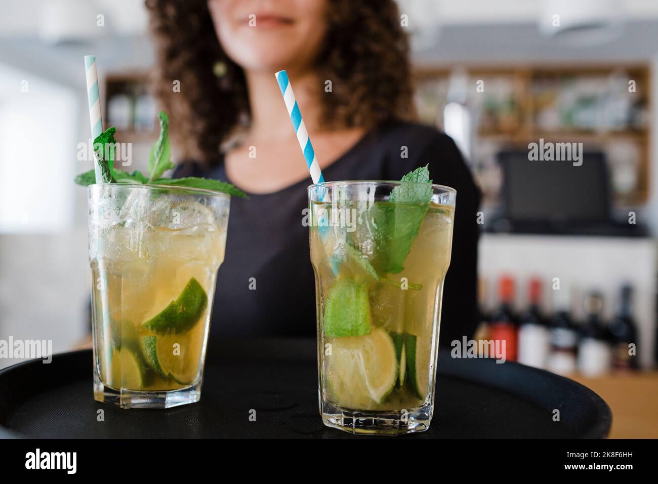 Junge Kellnerin mit Tablett serviert Cocktailgetränke im Restaurant Stockfoto