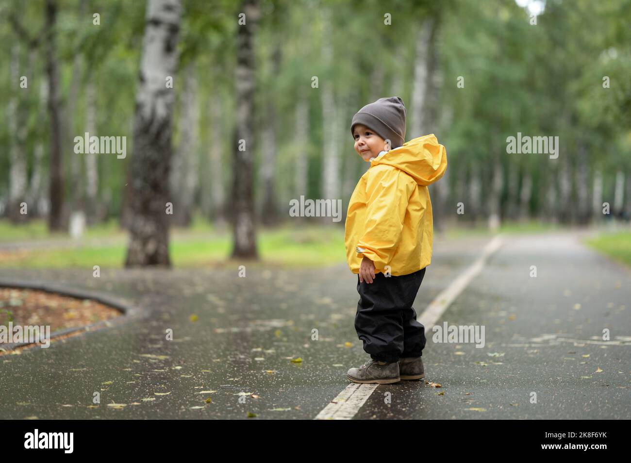 Kleiner Junge mit gelber Regenjacke auf der Straße Stockfoto
