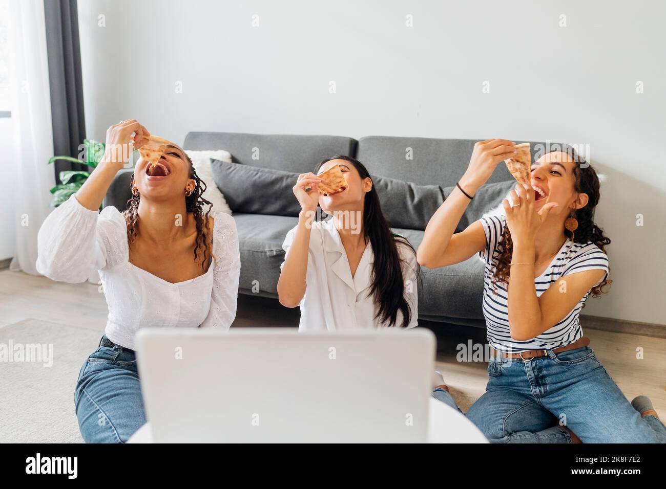 Glückliche Freunde essen Pizza Scheiben sitzen im Wohnzimmer Stockfoto